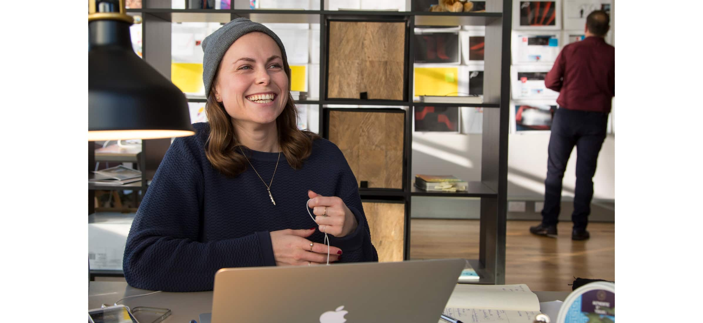 An employee of Future Kings smiling from behind a laptop in the office.